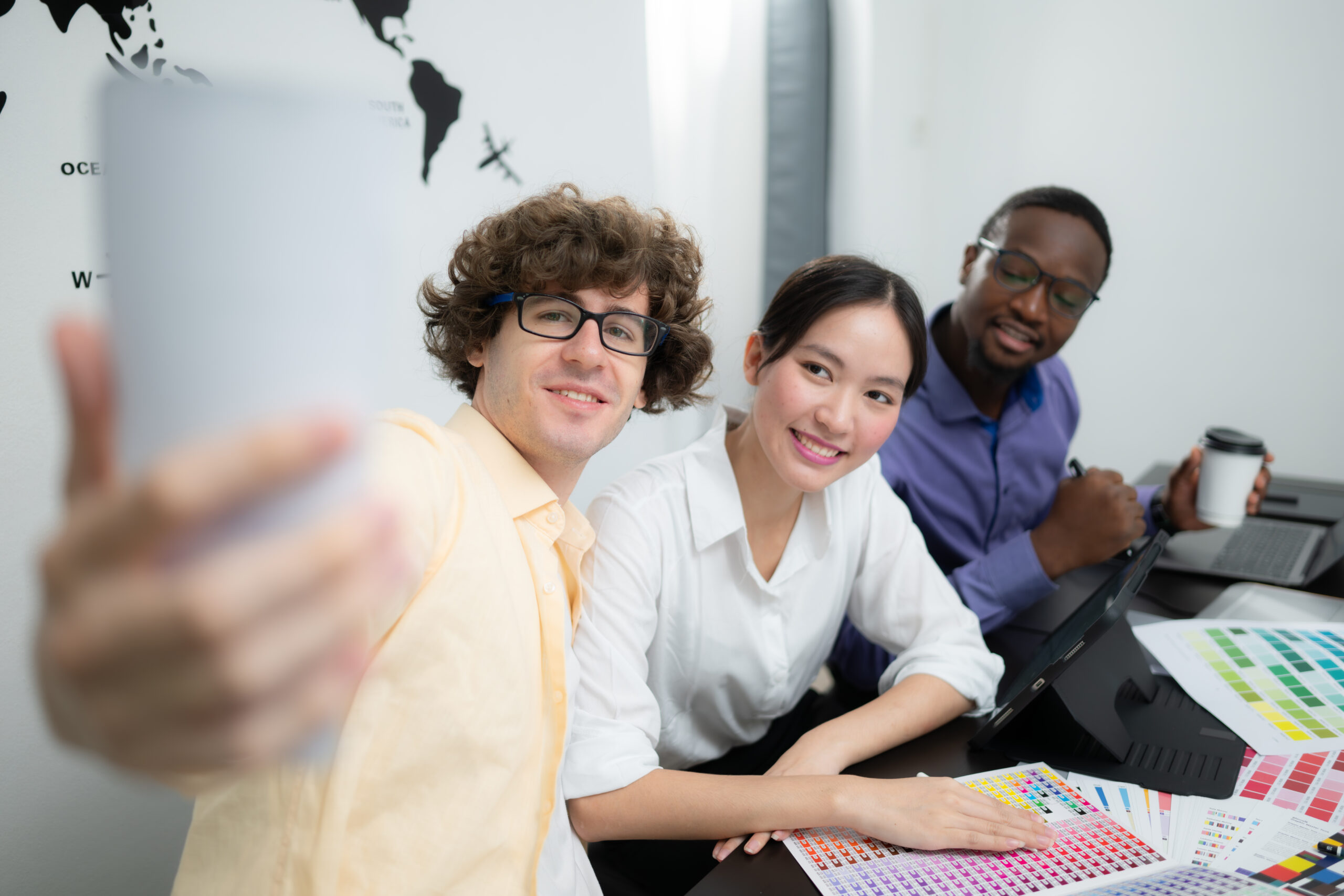 Multiethnic team of architects and designers are meeting to brainstorm design an application smartphone on a bright modern office working on a laptop.